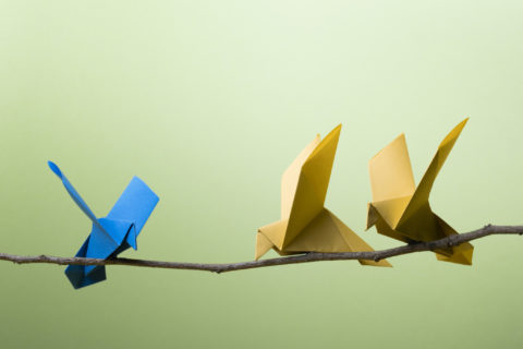 Drei Origamivögel sitzen auf einem Holzast